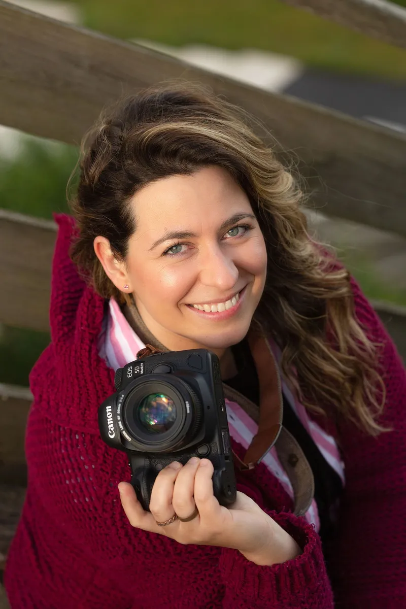 Priscila Ferreira sorridente, com a máquina fotográfica na mão