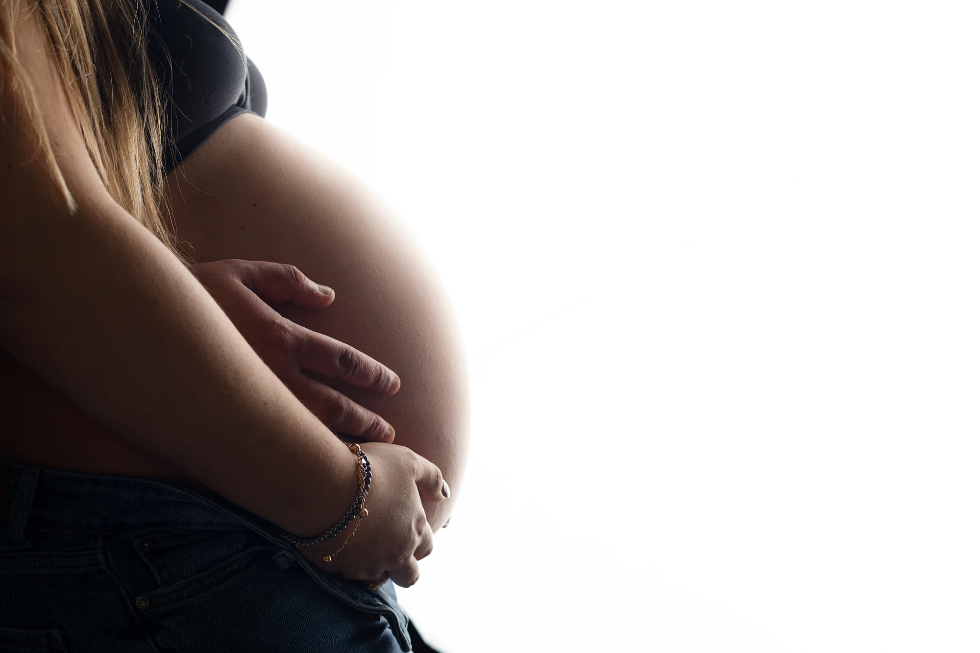 Silhueta de uma grávida com as mãos na barriga, em contraluz