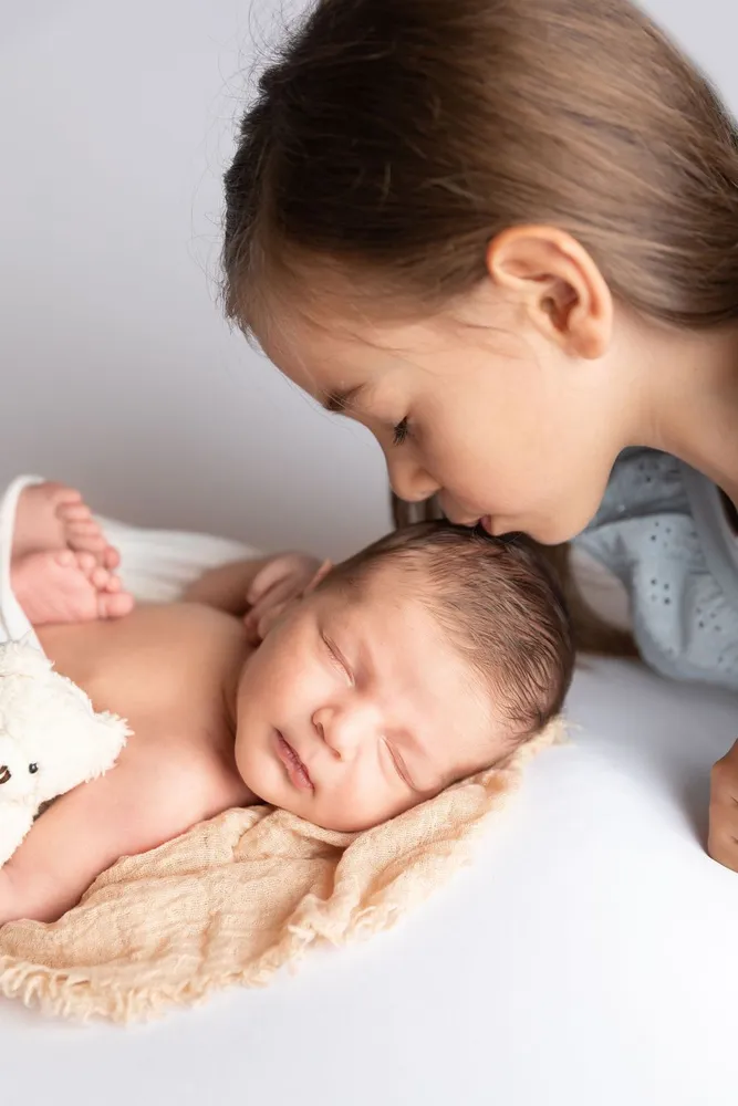 Irmã mais velha a dar um beijo ao bebé recém-nascido