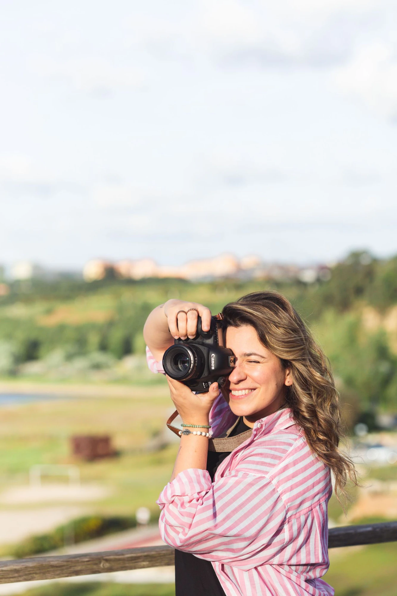Priscila Ferreira a fotografar ao ar livre, com a máquina junto ao rosto